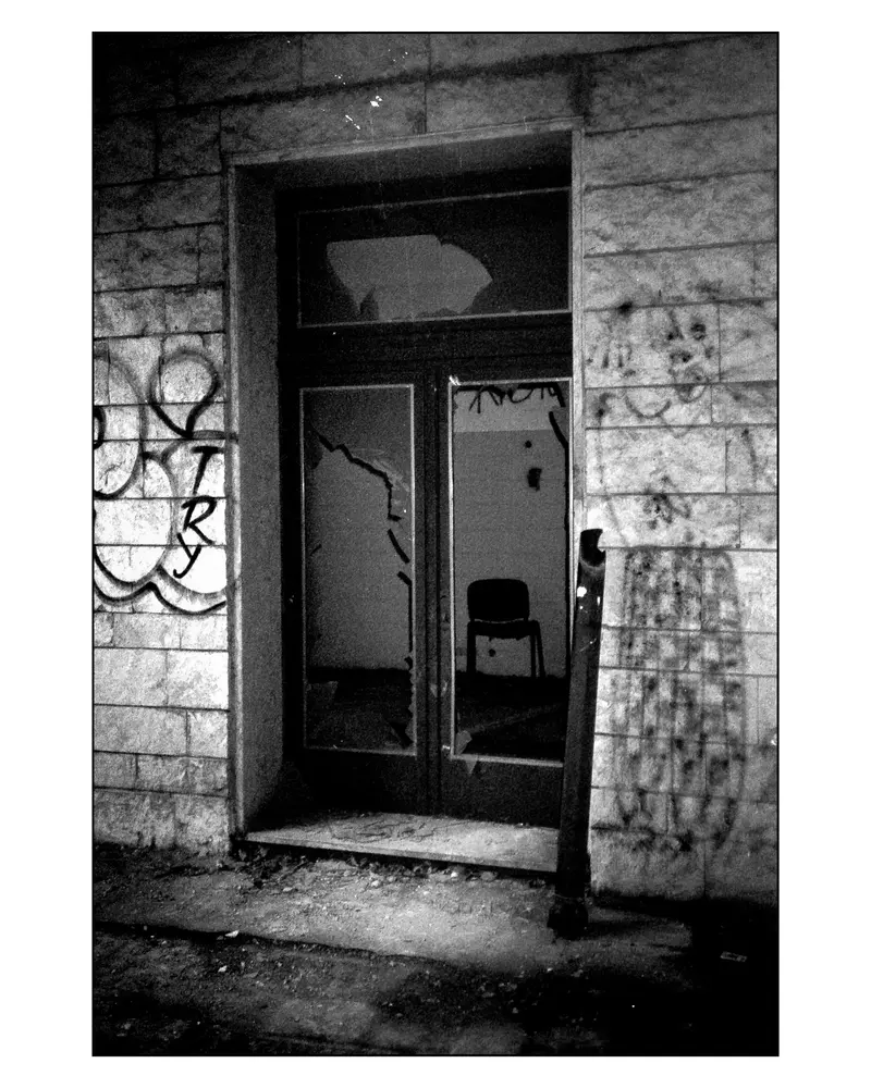 Abandoned Building Doorway with Broken Glass and Lone Chair, Villach–Grado Trip 2024