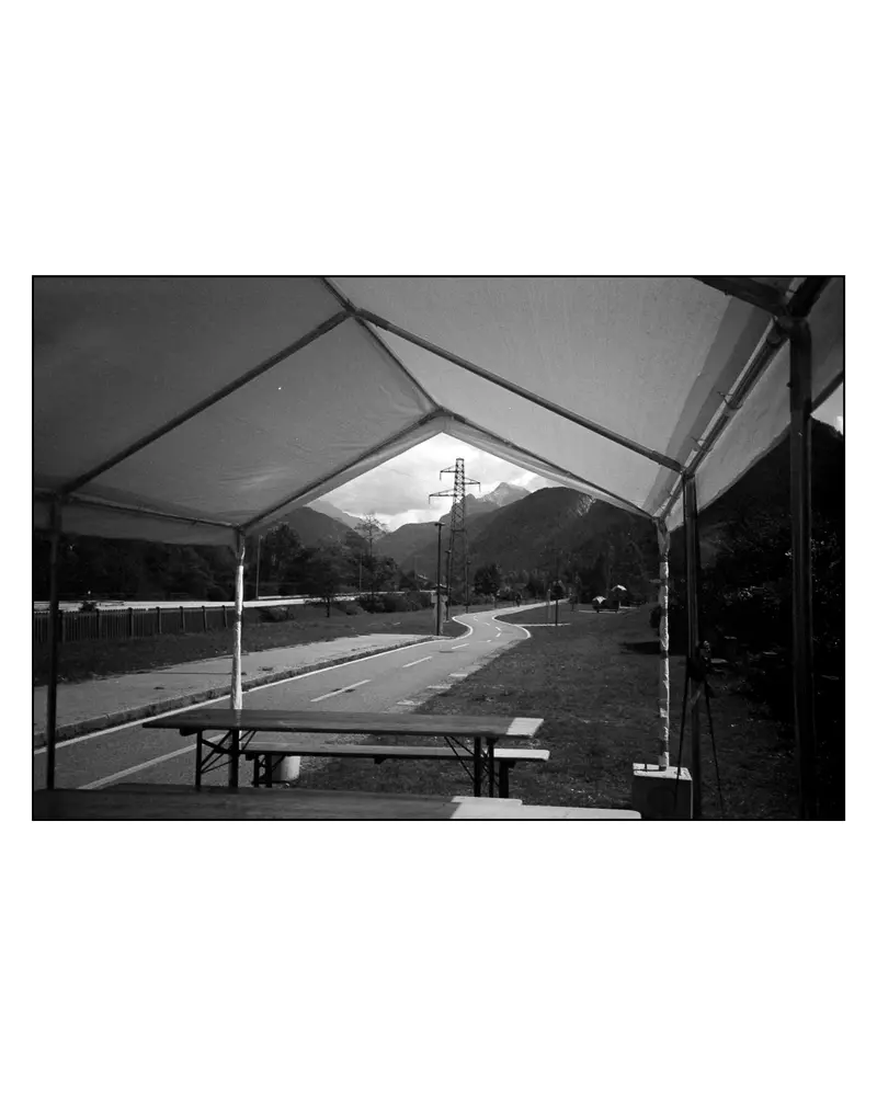 Empty rest-stop marquee with beer benches beside Alpe-Adria cycle path, Villach–Grado 2024