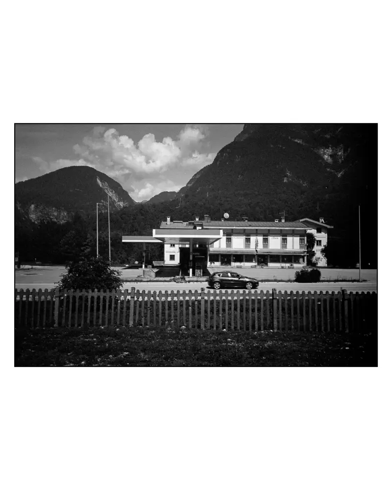 Roadside filling station and inn below alpine cliffs on the Villach–Grado cycling route, 2024