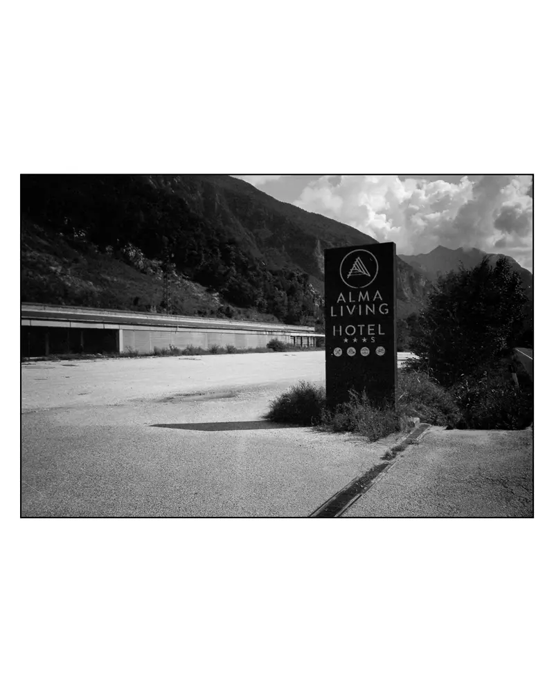 Alma Living Hotel roadside sign at empty Alpine car park, Villach–Grado route