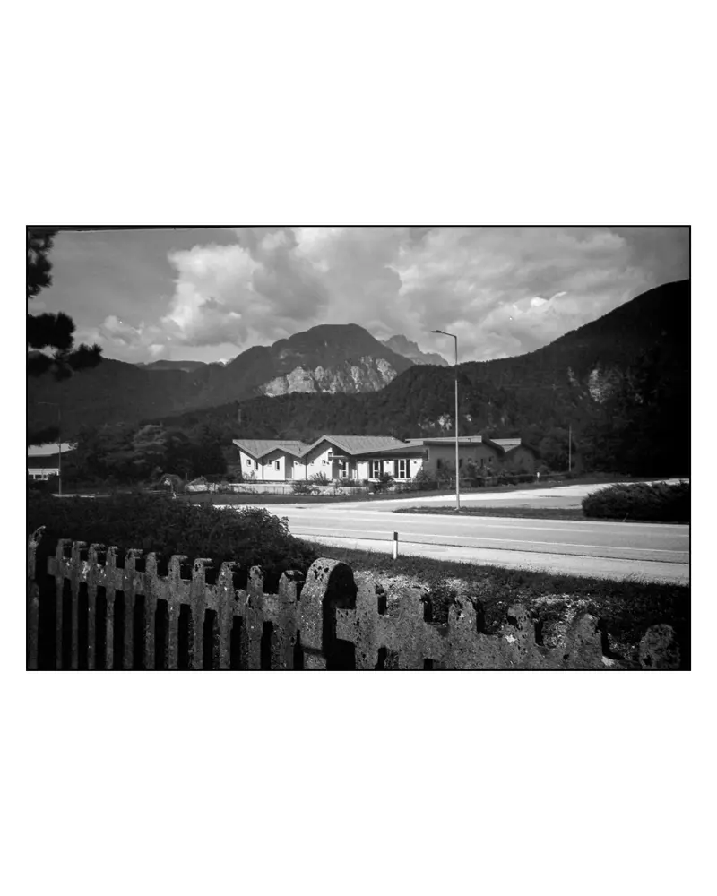 Roadside houses below limestone peaks on the Villach–Grado cycling route, 2024