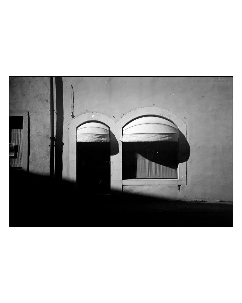 Arched doorway and window on rendered house facade, Grado, Italy, 2024