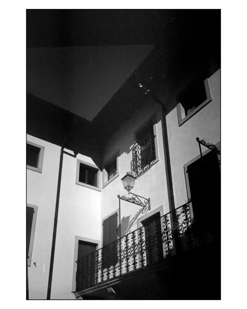 Wrought-iron balcony and wall lantern on an old-town façade, Grado, Italy