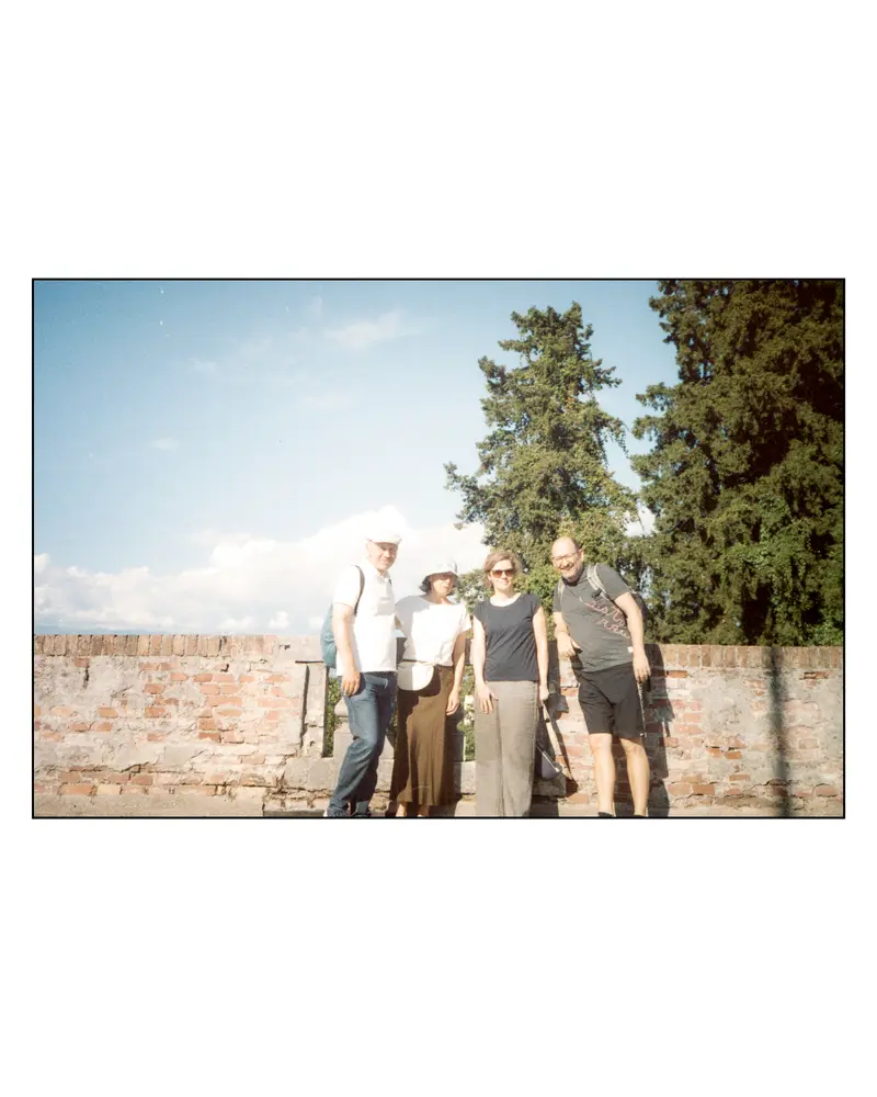 Four travellers pose at a brick wall during the 2023 Villach–Grado trip