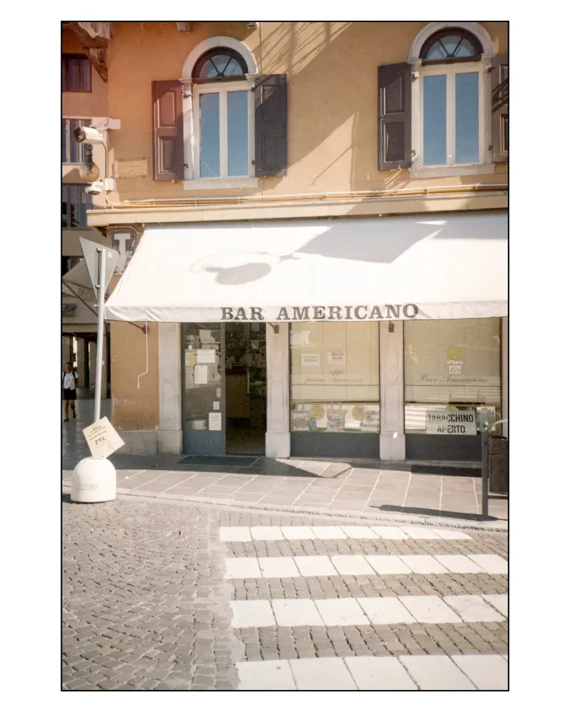 Bar Americano storefront with Tabacchino sign on cobbled street, Grado, Italy