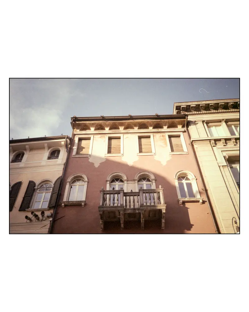 Venetian-style balustraded balcony on pink townhouse facade, Grado old town, July 2023