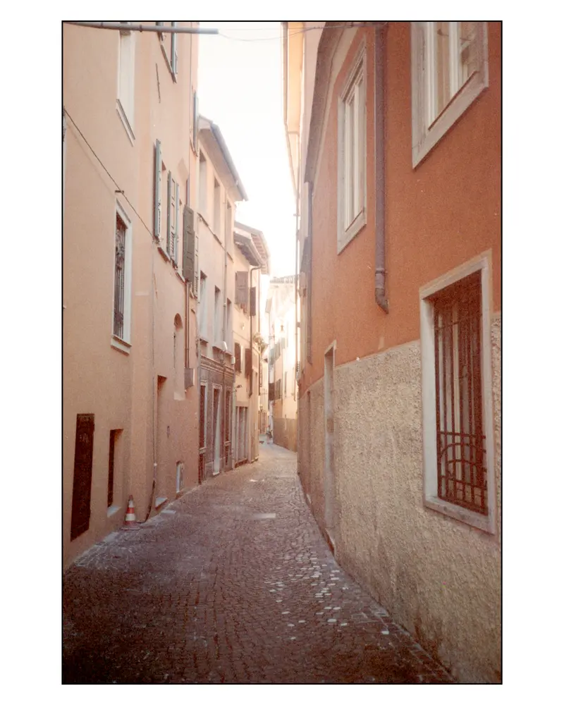 Narrow cobbled alley between pastel houses, Grado old town, December 2023