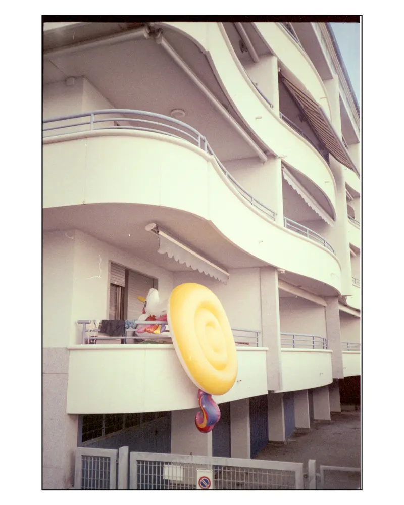 Inflatable pool floats drying on curved apartment balcony, Grado, Italy