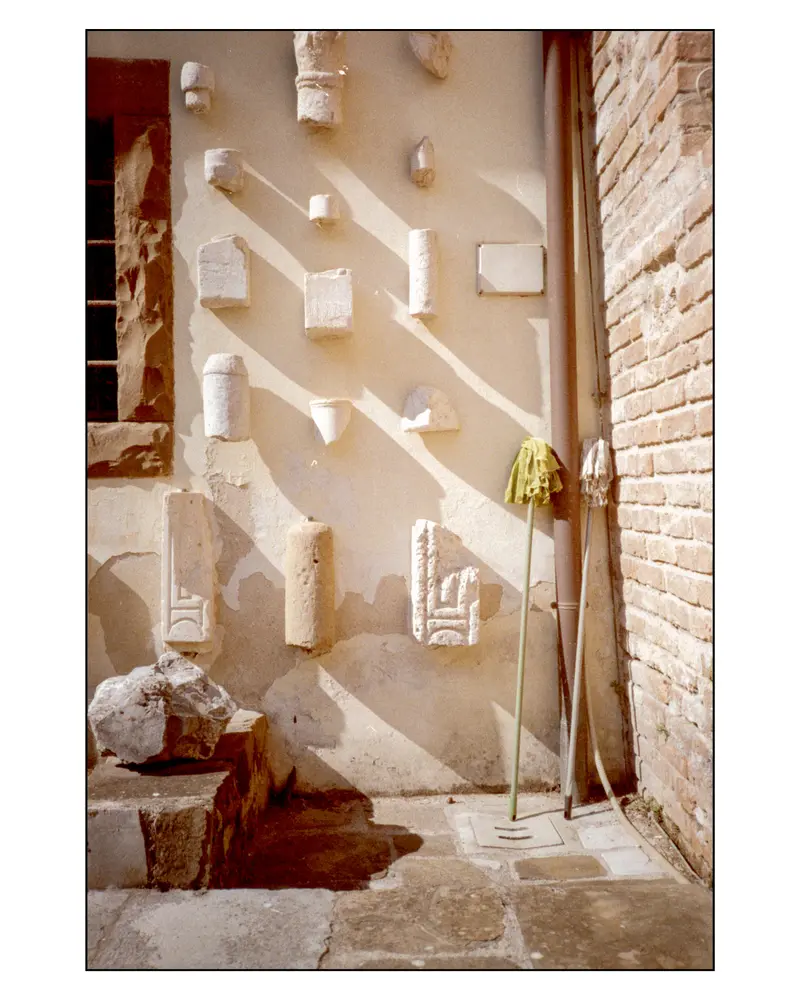 Roman and early Christian stone fragments mounted on lapidarium wall, Grado, Italy
