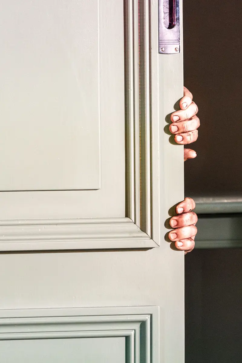 Fingers Gripping White Door Panel in Mysterious Partial Reveal