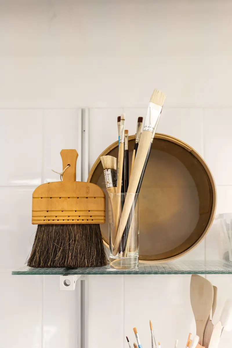 Art Studio Tools: Brushes, Dust Brush, and Ceramic Bowl on Glass Shelf
