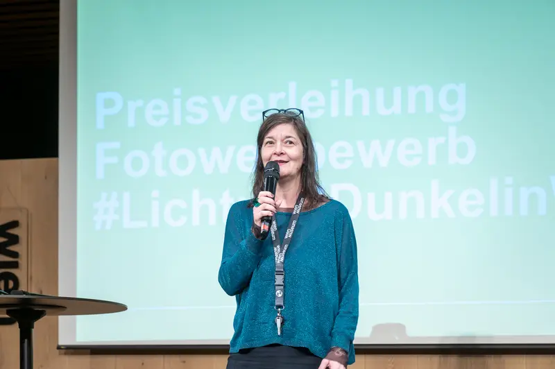 Speaker Presenting at Preisverleihung Fotowereb Event with Green Backdrop