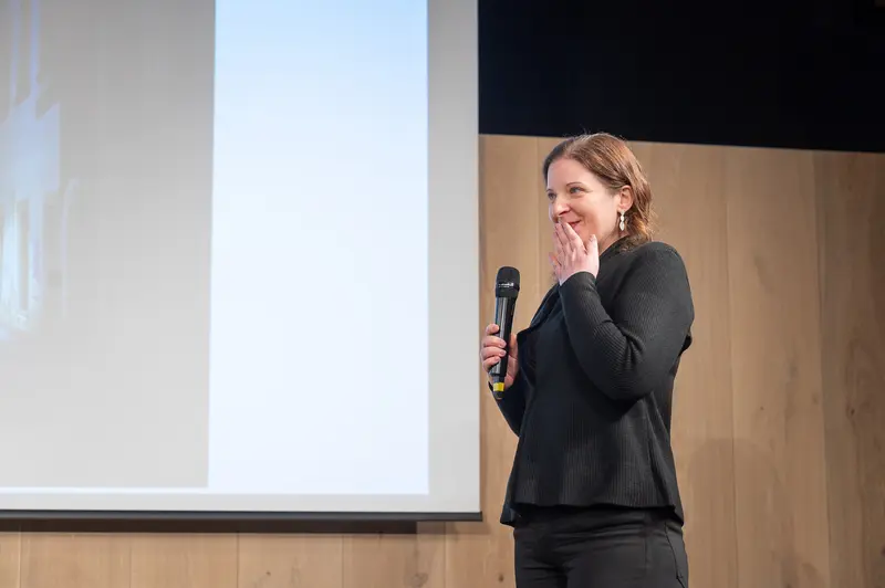 Speaker in Black Presenting at Professional Conference with Microphone