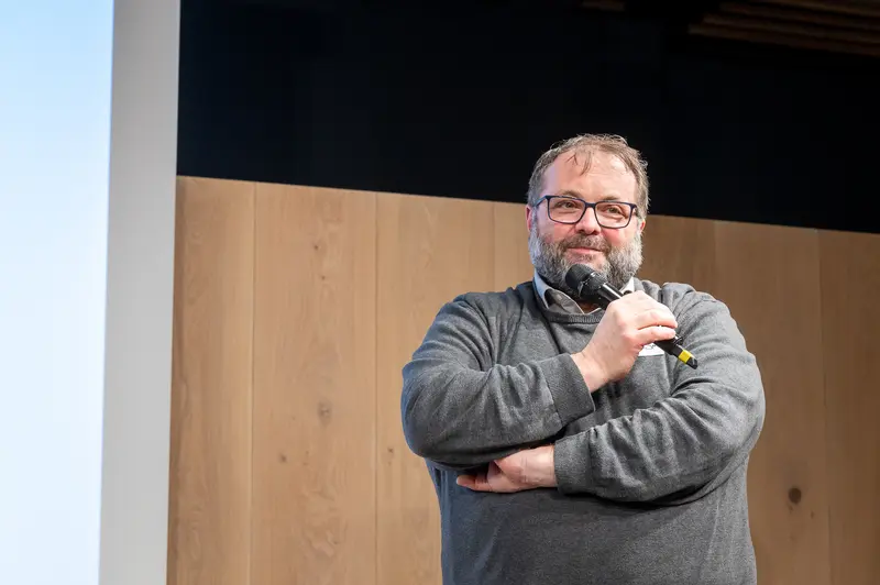 Speaker Presenting at Conference in Gray Sweater and Glasses