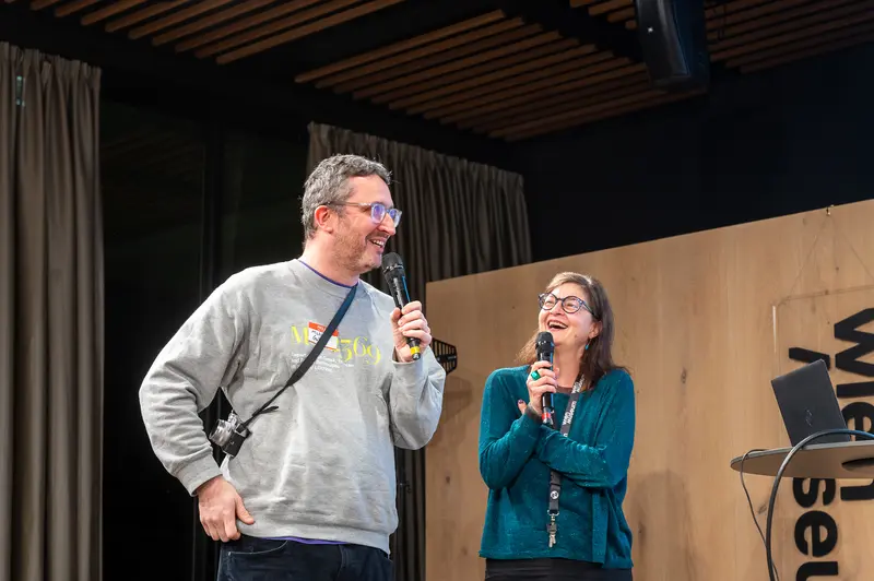 Two Speakers with Microphones on Stage at Technology Event