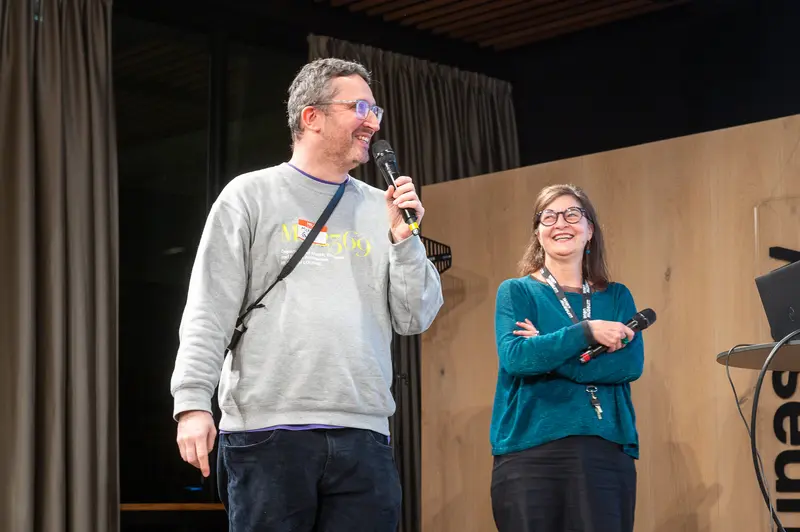 Conference Presenters Sharing Microphone with Engaging Smiles on Stage