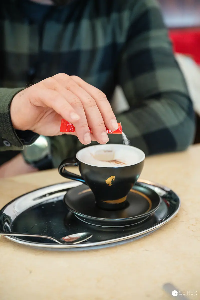 Hand Adding Sugar to Black Coffee Cup at Cafe Museum, Vienna