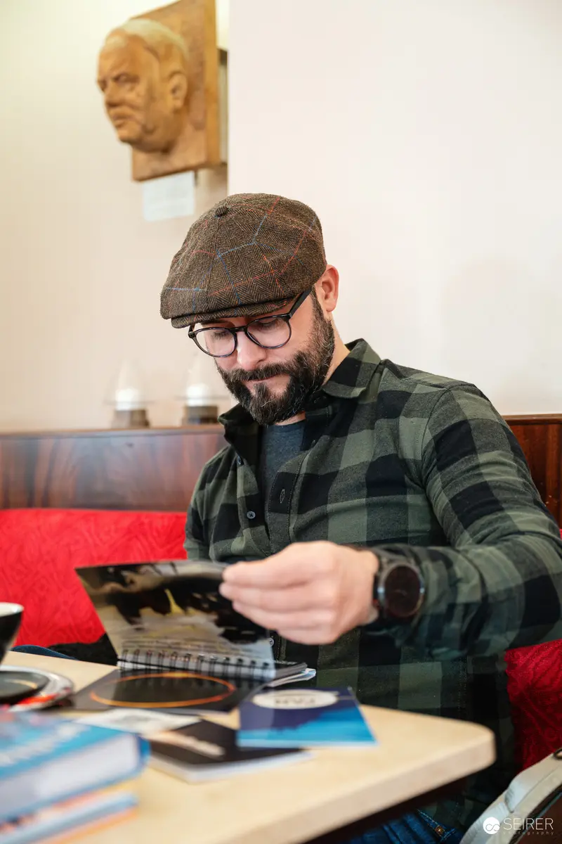 Falk Holzapfel Working at Cafe Museum in Vintage Plaid Jacket and Flat Cap