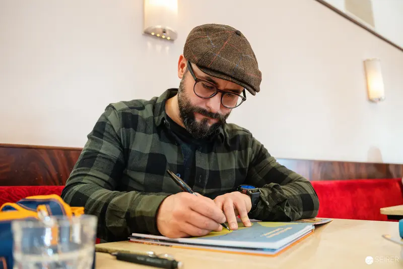 Writer in Plaid Cap Working at Cafe Museum in Vienna