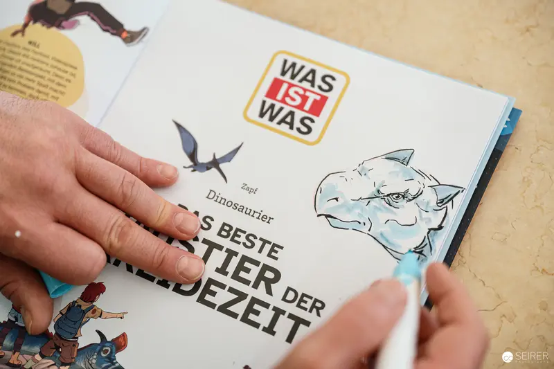 Dinosaur Exploration in Children's Book: Hand Pointing at Prehistoric Animal Illustration