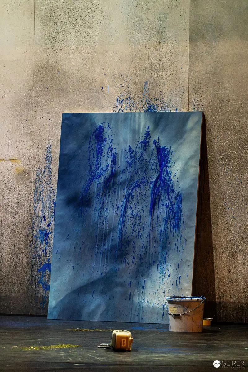 Blue Abstract Artwork Leaning Against Weathered Wall with Paint Bucket