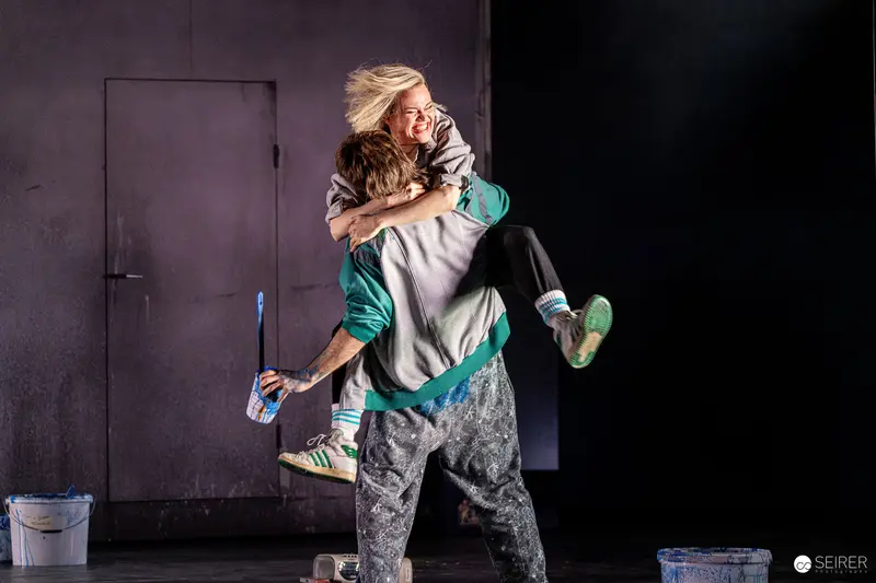 Intense Emotional Embrace During Theatrical Rehearsal of "Azur oder die Farbe von Wasser"