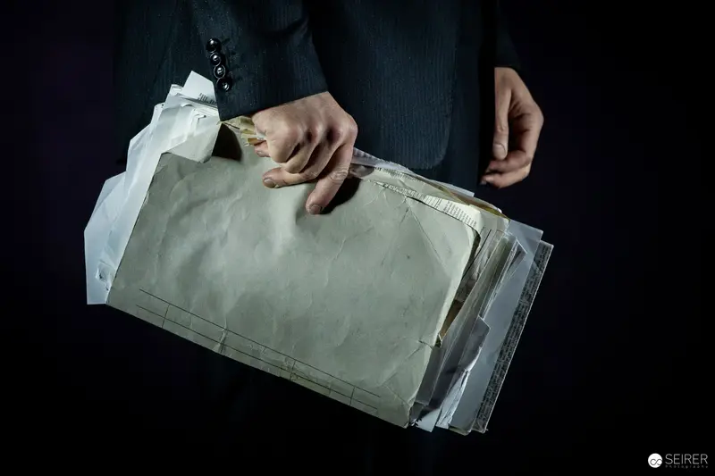 Mysterious Envelope Held by Partially Visible Person in Dark Setting