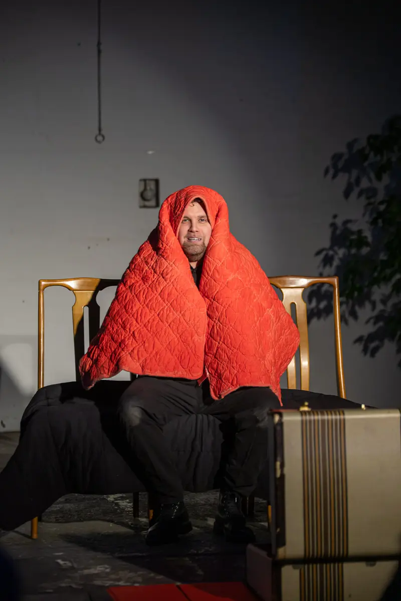 LINE RUNNER 2024: David Czifer Wrapped in Red Quilted Blanket on Stage