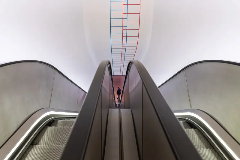 Geometric Escalator Perspective with Colored Vertical Grid in Modern Interior