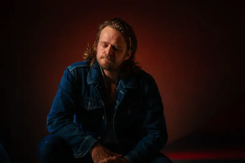 Contemplative Actor in Blue Denim Jacket During Theatrical Photoshoot