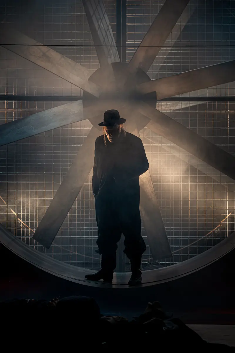 Mysterious Silhouette in Industrial Setting Wearing Fedora and Coat