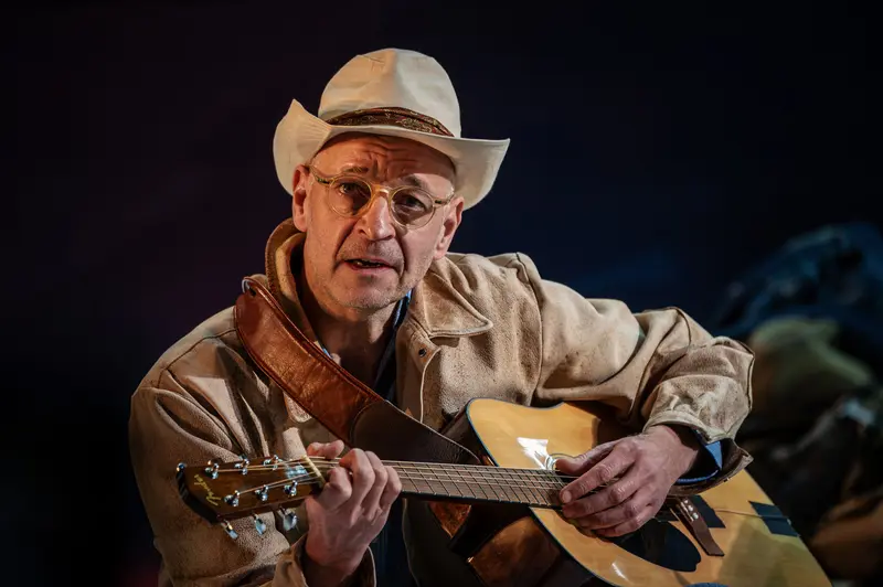 Acoustic Guitarist in Western Attire Performing Intimate Stage Performance