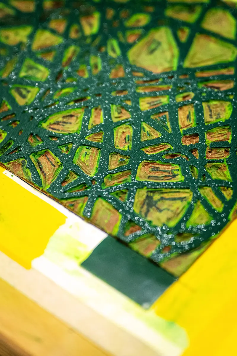 Intricate Green and Yellow Mosaic Pattern on Textured Surface