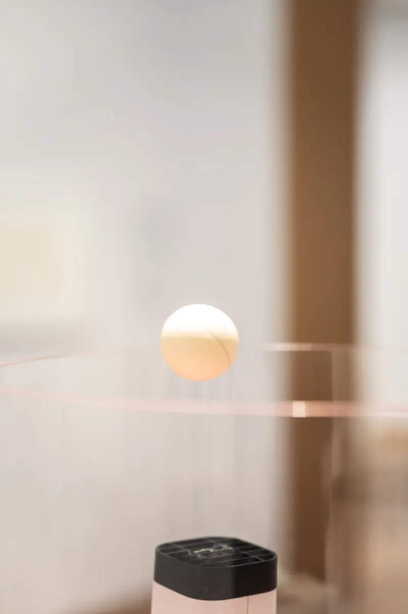 Levitating Glowing Sphere Above Black Minimalist Object in Soft Light