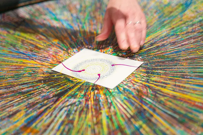 Hand Creating Radial Color Burst Painting on Textured Multicolor Background