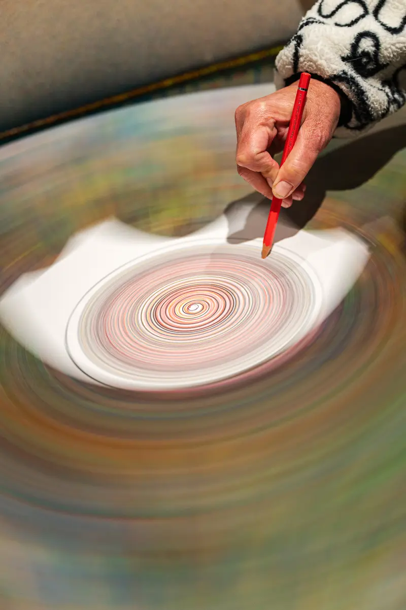 Artist Creating Concentric Spiral Drawing with Red Marker on Spinning Surface