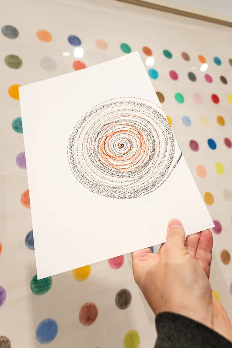 Hand Holding Abstract Spiral Drawing Against Colorful Dotted Background