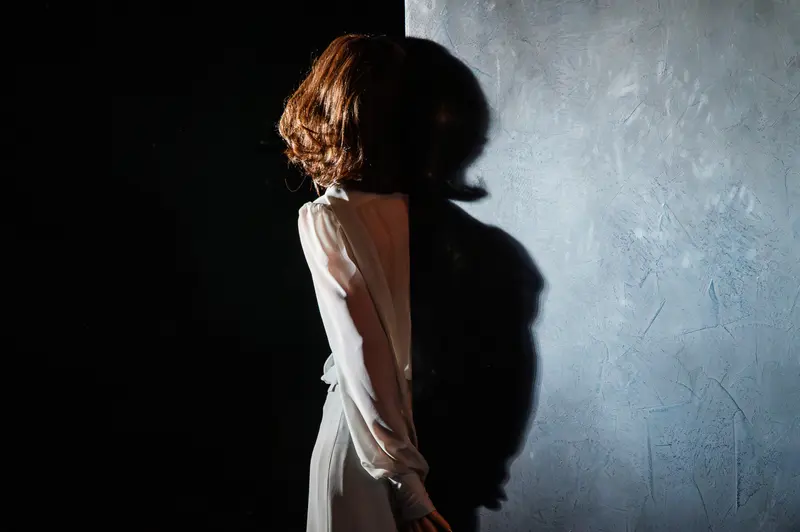 Contemplative Figure Casting Shadow in Dramatic Theatrical Lighting