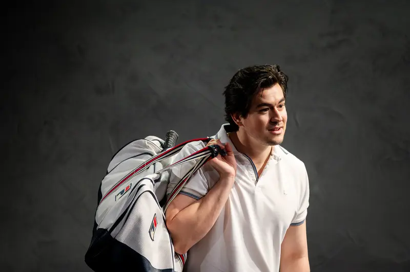 Professional Athlete with Tennis Racket Bag Against Dark Background
