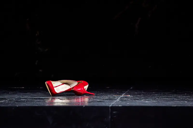Red High-Heeled Shoe Dramatically Positioned on Dark Theater Stage Floor