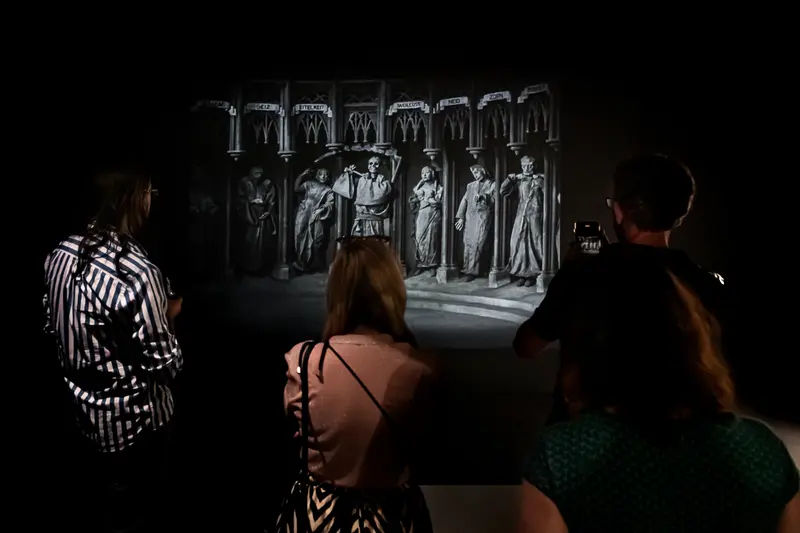 Museum Visitors Observing Black and White Historical Architectural Projection