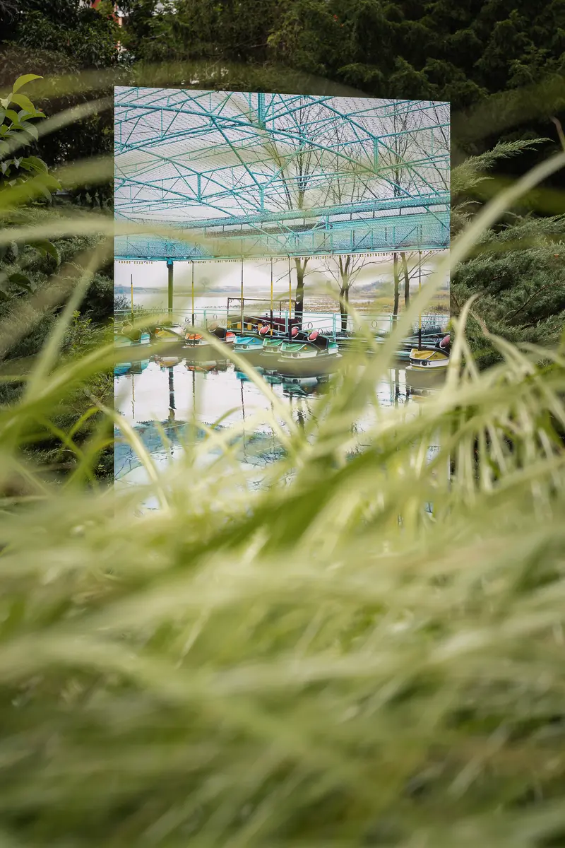 Reflective Greenhouse Scene Through Blurred Grass Blades