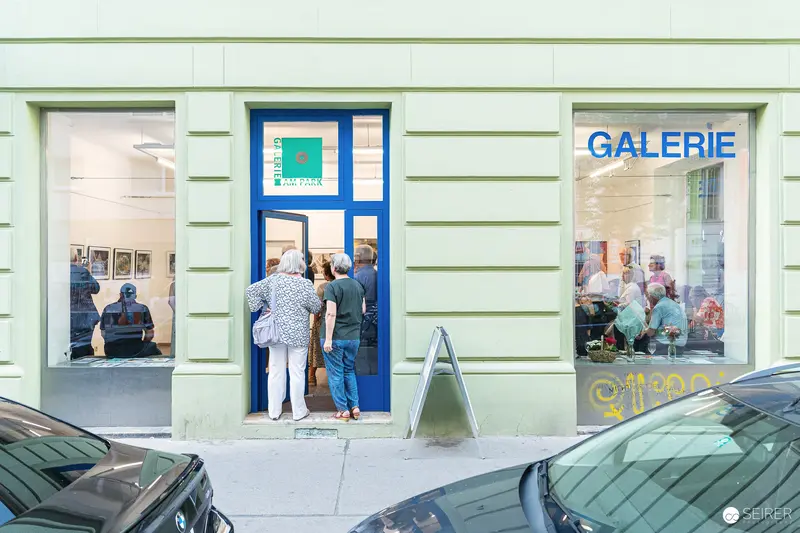 Visitors Gather at Blue-Framed Galerie Entrance During Vernissage Exhibition