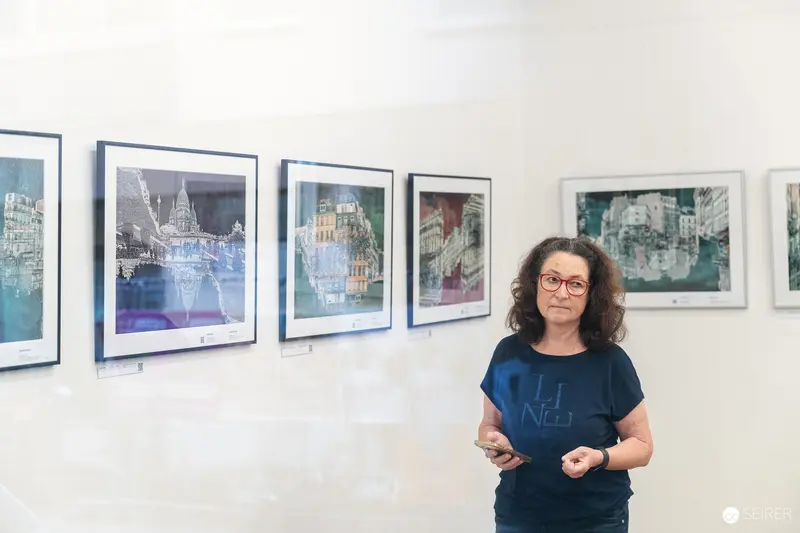 Curator Standing Amid Urban Landscape Artworks at "Ladypower" Exhibition Vernissage