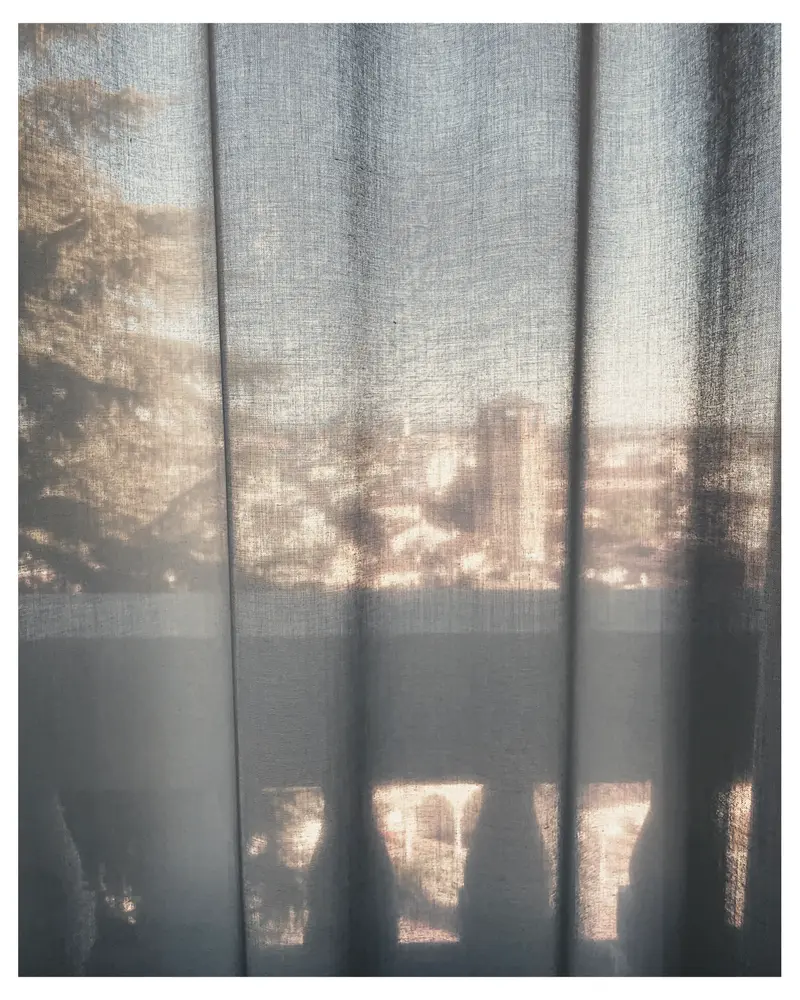 Sunlight Filtered Through Sheer Curtains Revealing Urban Landscape