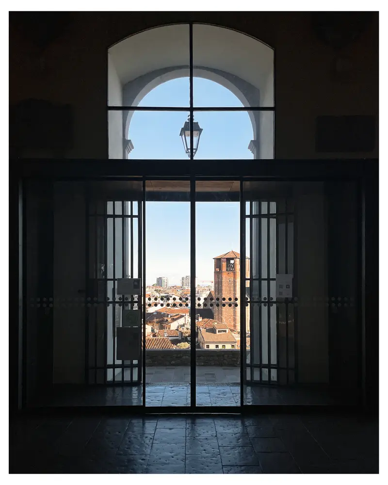 Arched Window View of Historic Towers in Udine, Italy