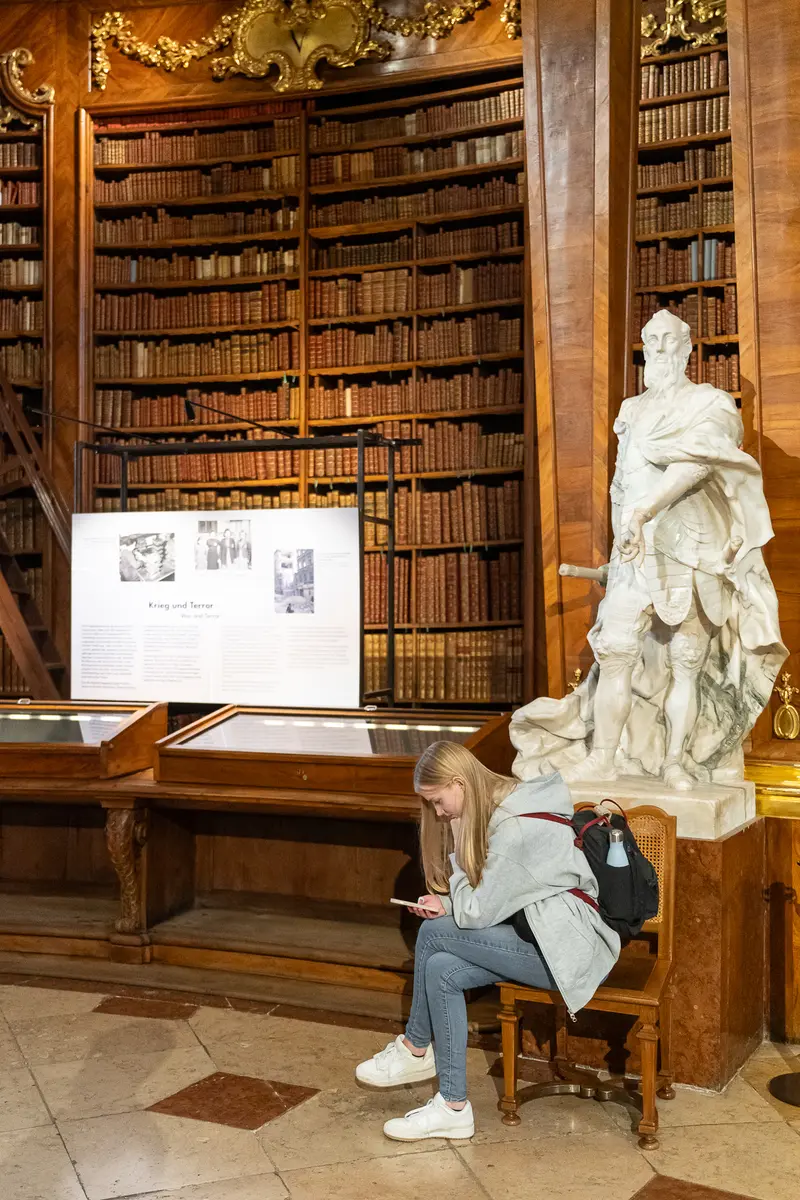 Young Researcher Studying Amid Baroque Library Stacks and Marble Sculpture