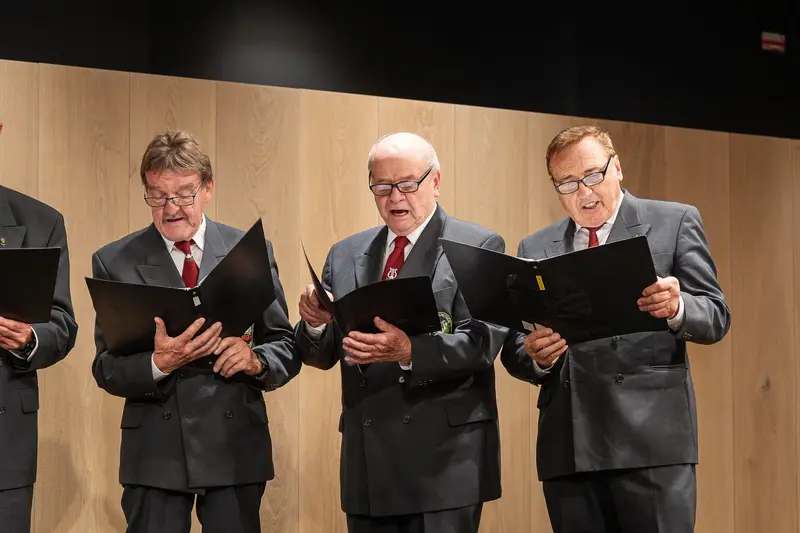 Elderly Choir Singers Performing at Formal Event in Matching Dark Suits