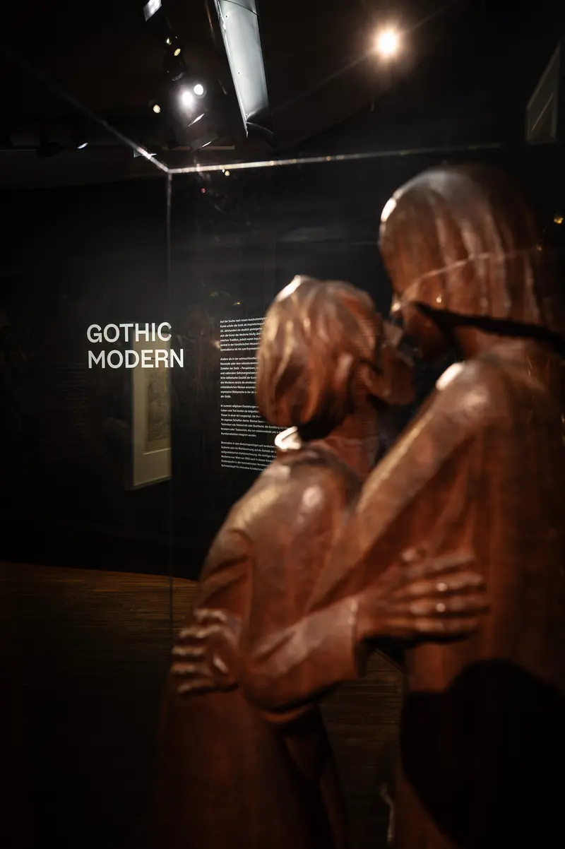 Gothic Modern Exhibition: Wooden Sculptural Figures in Dark Gallery Space