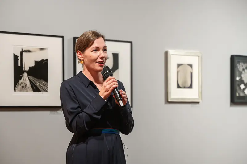 Woman Speaking at Photography Exhibition Opening with Black and White Art